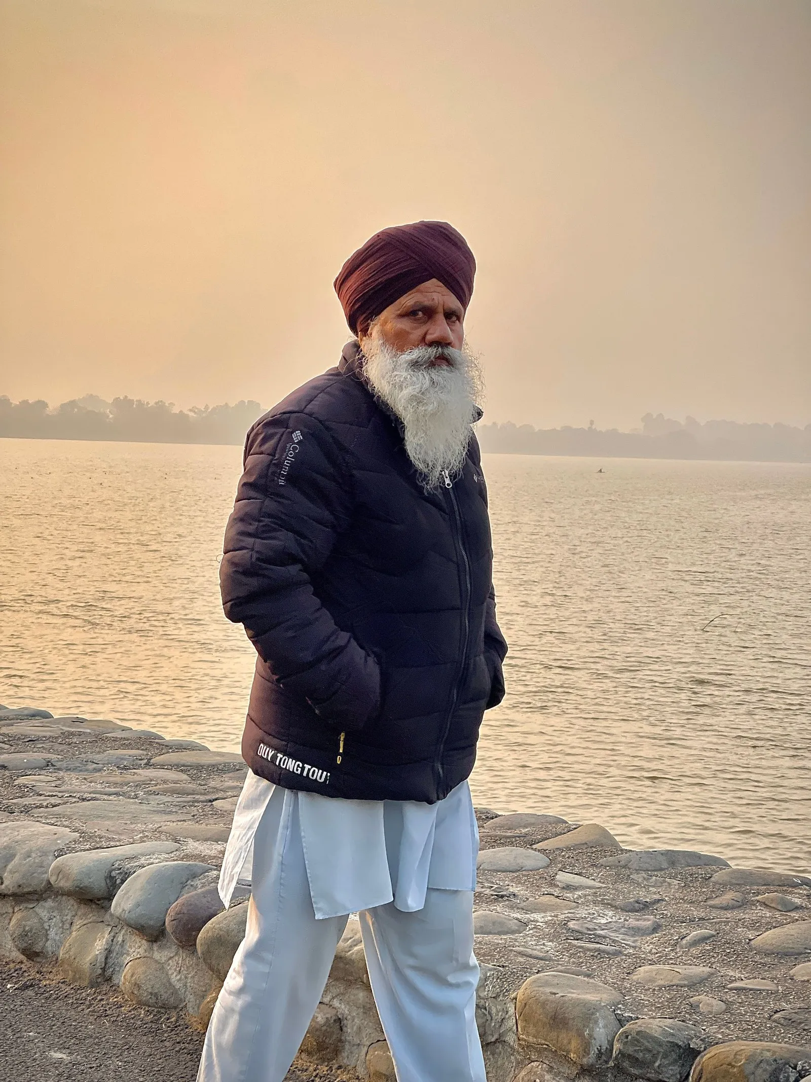 An elderly Sikh man walking by the lake at sunset, Chandigarh