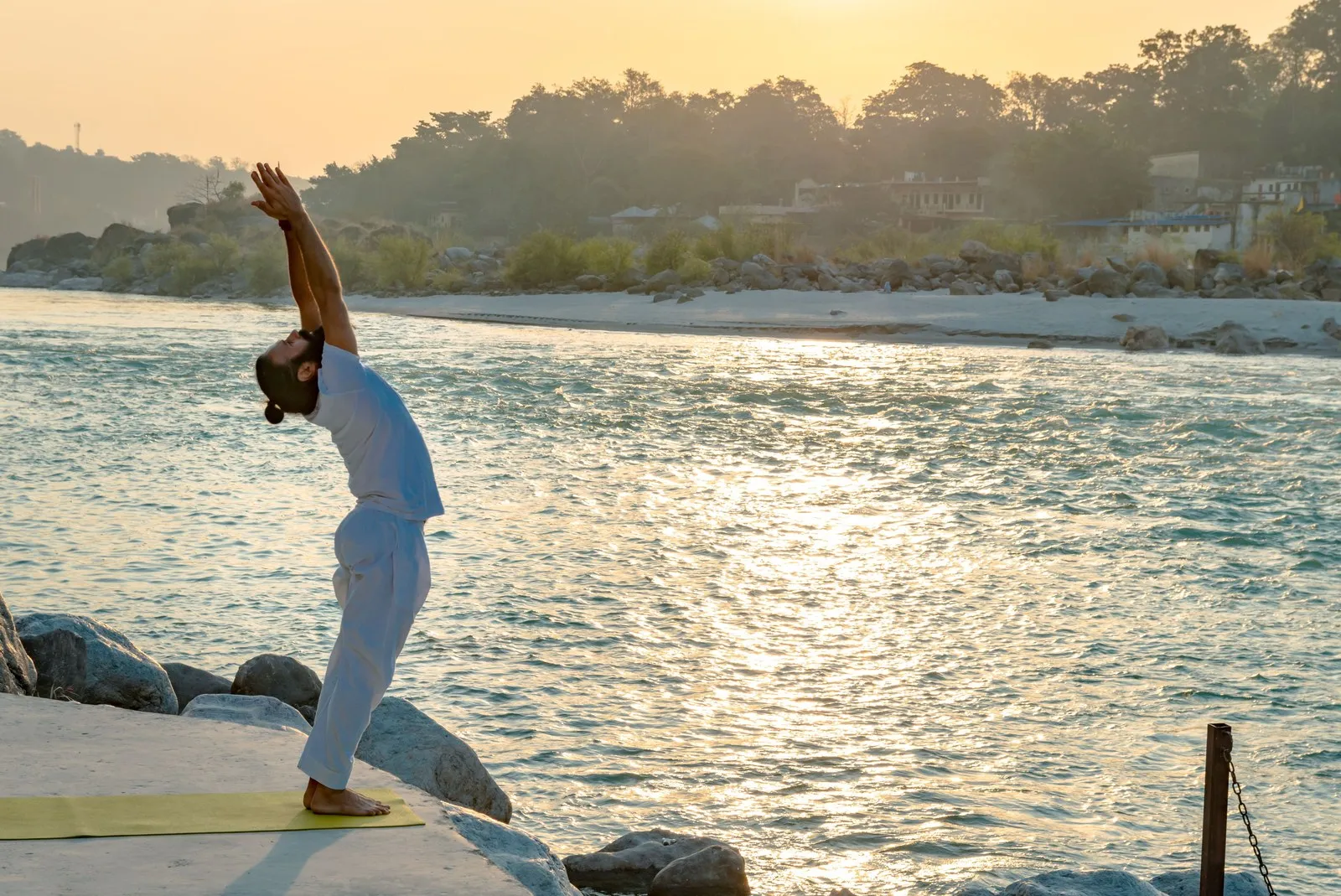 A man at his yoga practice by the Ganga at sunrise, Rishikesh